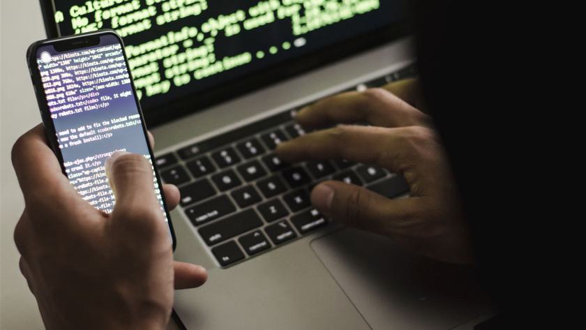 Nicht Erkennbarer Hacker Mit Smartphone Eingabe Auf Laptop Am Schreibtisch