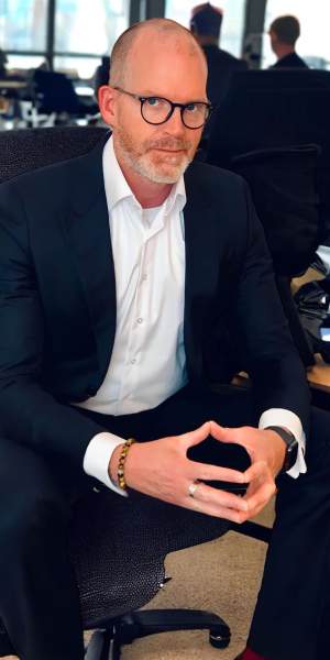 Paul Malberg im Büro mit Staff im Hintergrund